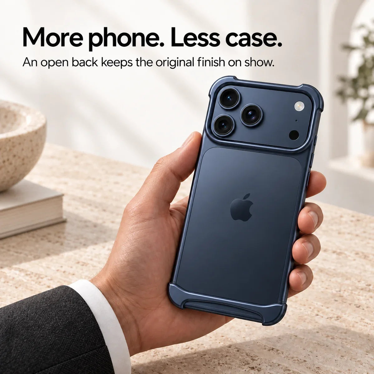 Dark blue metal phone bumper held above a pale stone desk, showing the exposed phone back #color_Deep Blue